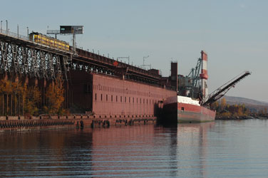 The Joseph H. Thompson loading at Taconite Harbor with an LTV train unloading on the dock.